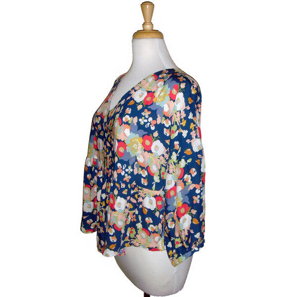This v neck blouse features a gorgeous coral and white floral print on a blue background, paired with a 3/4 gathered sleeve and flowing body for a fun and pretty look. Perfect for any occasion!