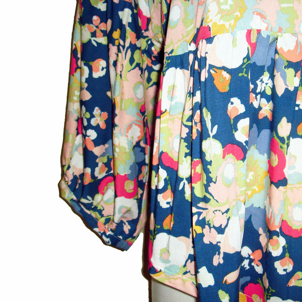 This v neck blouse features a gorgeous coral and white floral print on a blue background, paired with a 3/4 gathered sleeve and flowing body for a fun and pretty look. Perfect for any occasion!